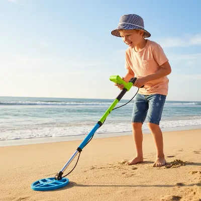 A young child with a lightweight, adjustable metal detector exploring a sandy beach.